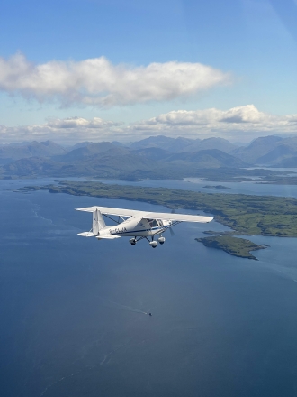 Formation flugelling, by James Alexander. “Sim Culpin and Gordon Morrison in their C42 on the way home to Balado from the Glenforsa fly-in after the perfect overnight stay.